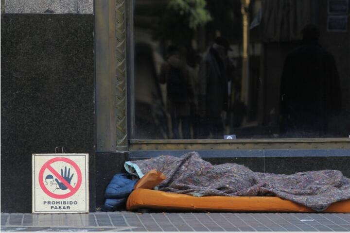 Persona durmiendo en la calle tapada con una frazada